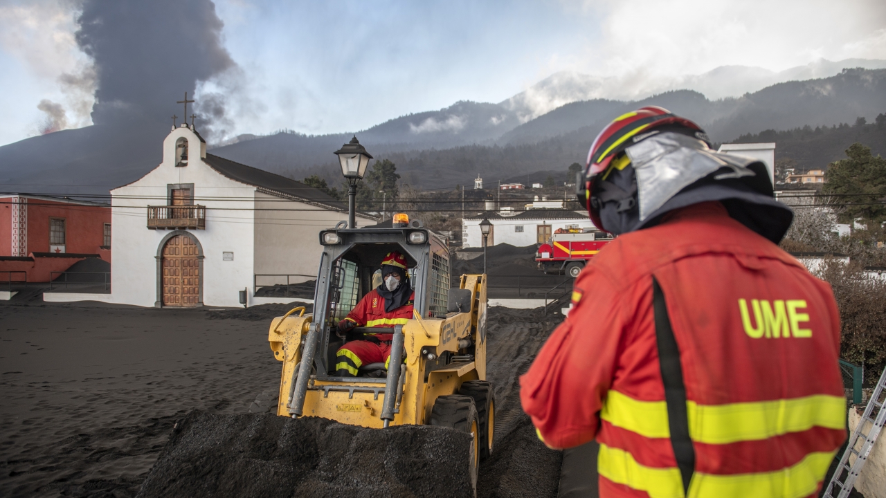 Military Emergency Unit personal clear black ash from a volcano as it erupts on the Canary island of La Palma, Spain.