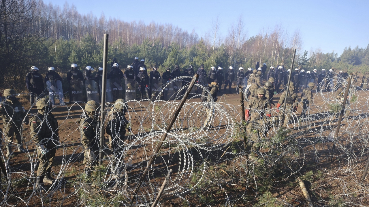 A photo of Polish police and border guards standing near barbed wire at the Belarus-Poland border.
