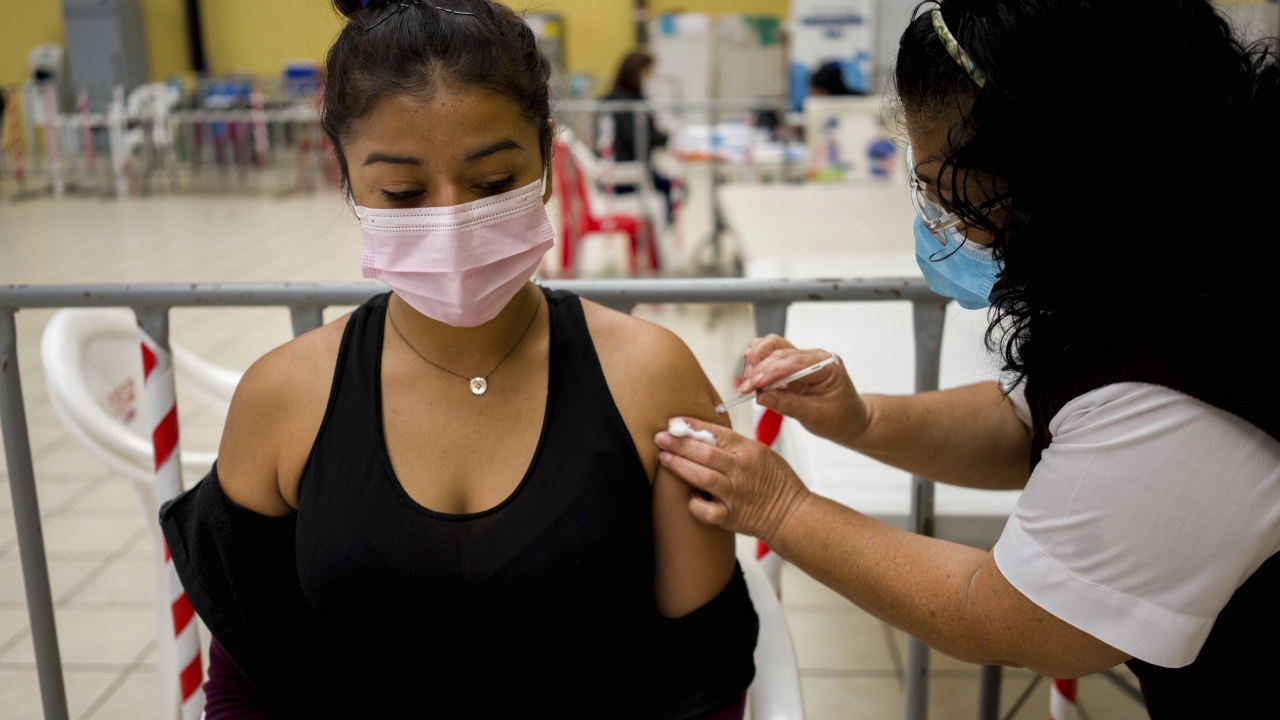 A health care worker administers a COVID-19 vaccine
