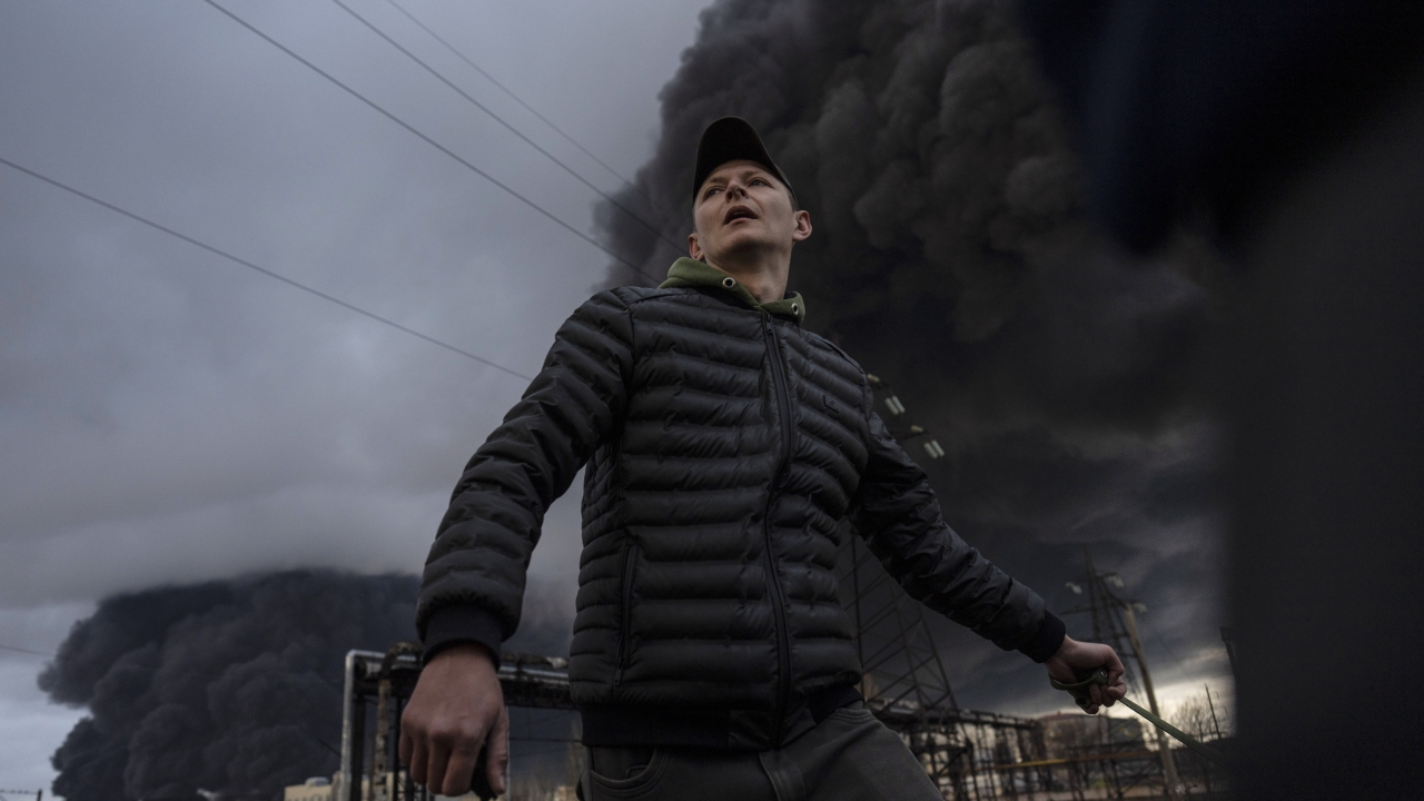 A man stands as smoke rises in the air in the background after shelling in Odesa, Ukraine