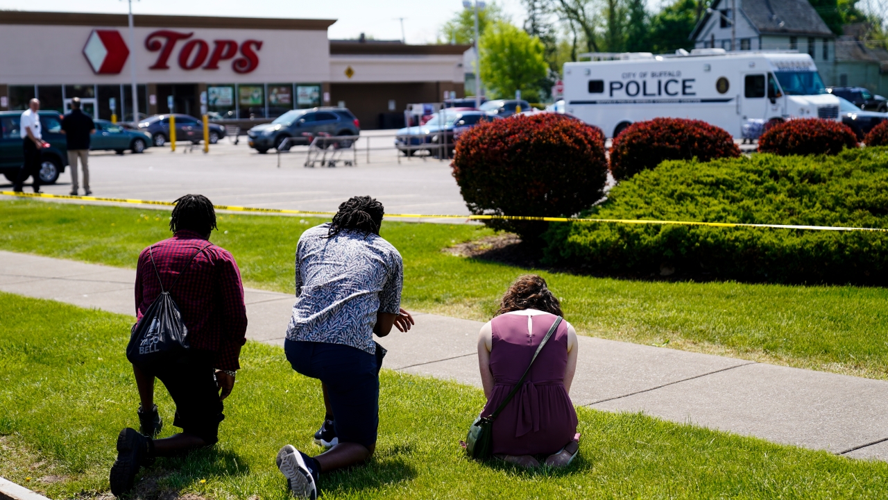 People pray outside the scene of a deadly mass shooting