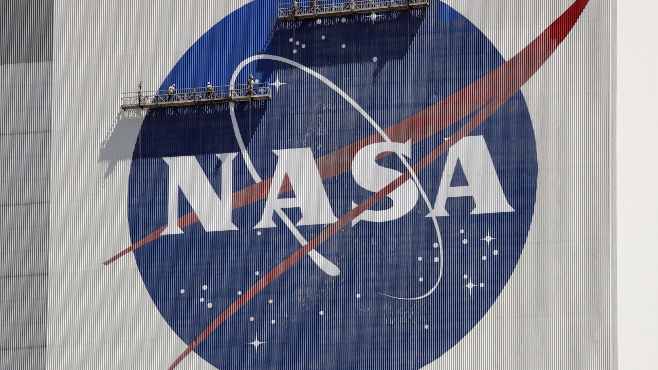 Workers painting the NASA logo