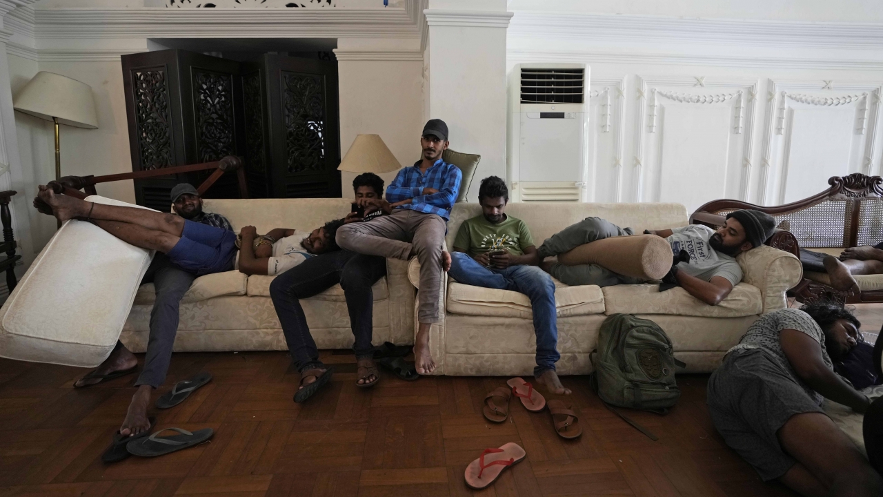 Protesters rest on sofas in the living hall of prime minister's official residence a day after vandalising it