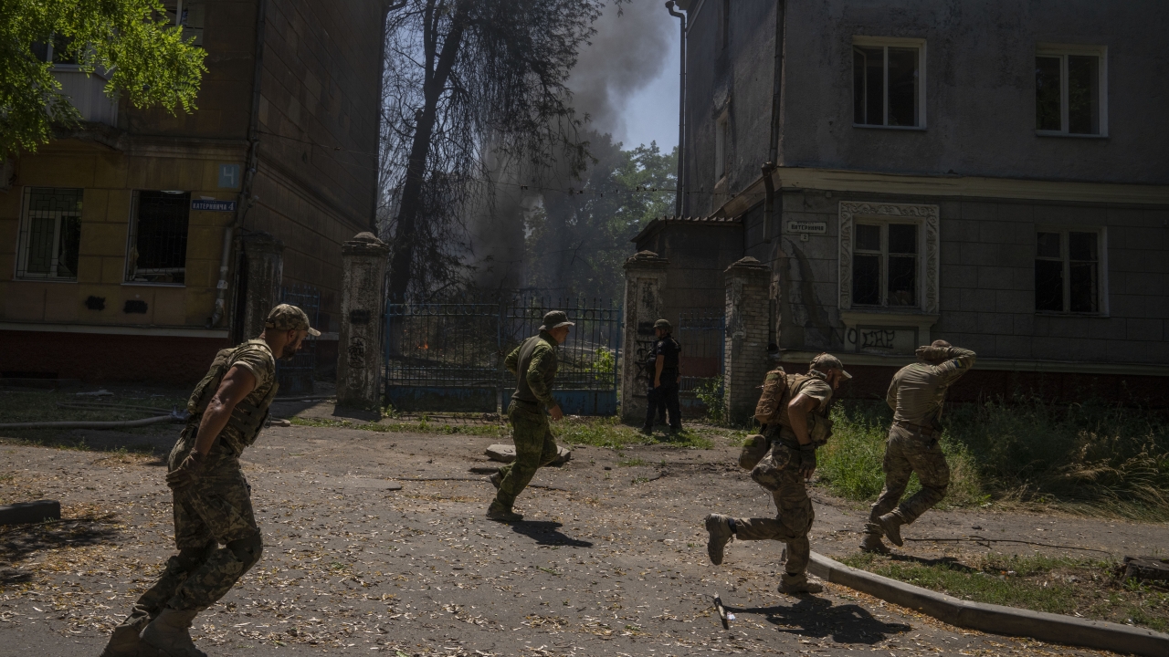 Ukrainian soldiers run after a missile strike hit a residential area