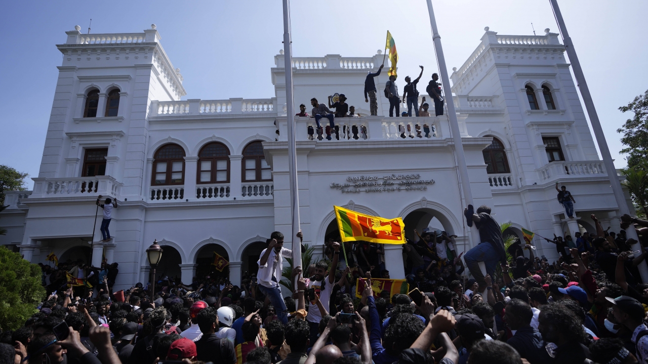 Protesters stand with others on top of the building of Sri Lankan Prime Minister Ranil Wickremesinghe's office