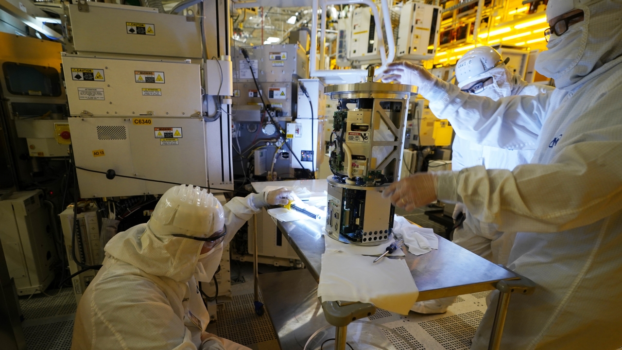 Technicians inspect a piece of equipment at the Micron Technology automotive chip manufacturing plant.