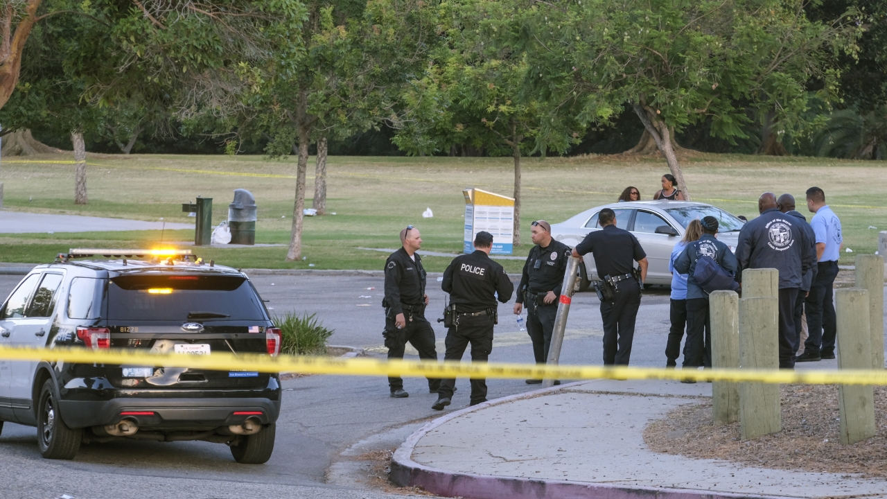Police officers stand near the scene of a shooting at Peck Park in San Pedro, Calif.