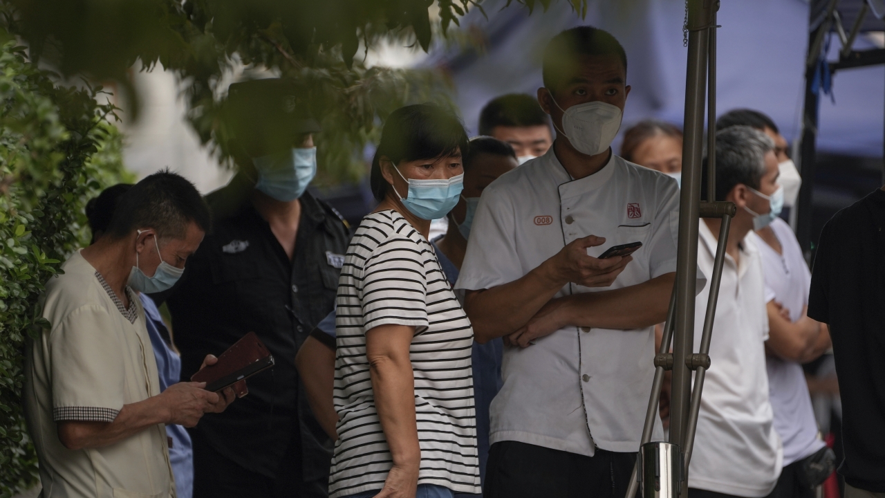 Residents wearing face masks wait in line to get their routine COVID-19 testing in Beijing