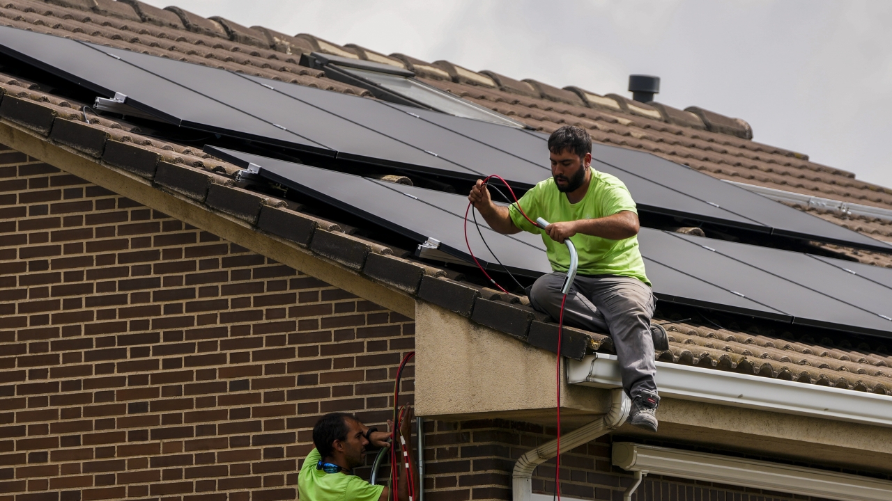 Workers install solar panels on a house.