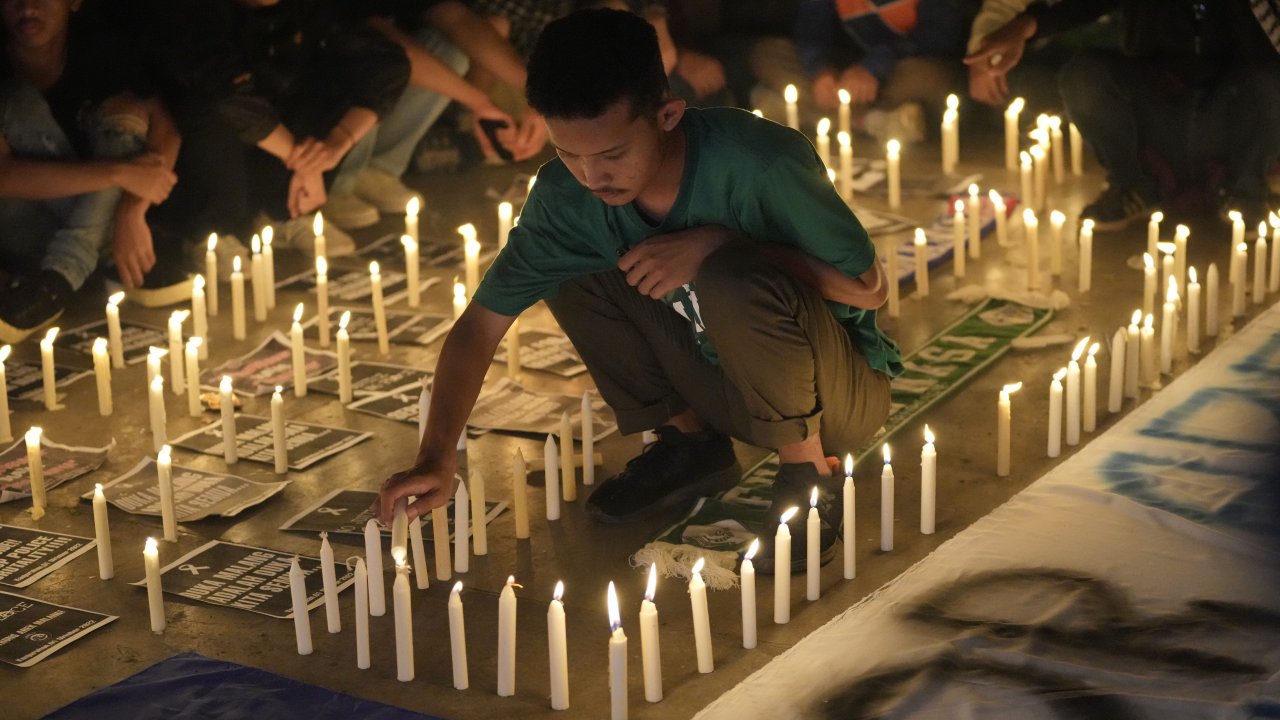 A man lights a candle during a candle light vigil for Arema FC Supporters who died following a soccer match stampede.