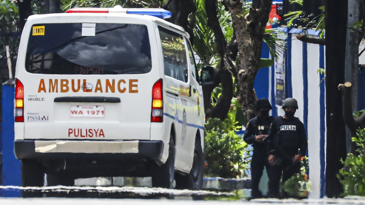 Police keep watch as an ambulance is parked outside the PNP Custodial Compound in Camp Crame police headquarters.
