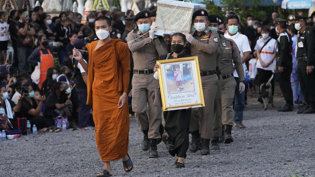 Police carry a coffin containing a victim in the day care center attack for cremation in Thailand.