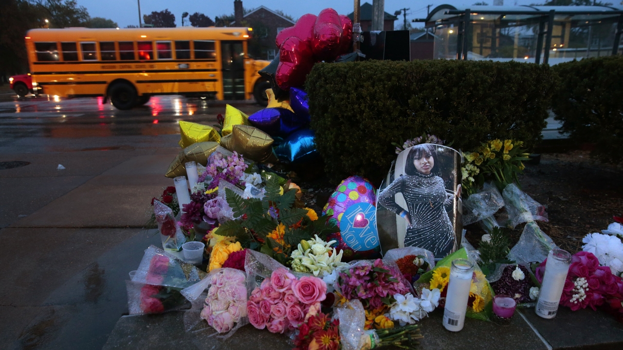 A photo of Alexzandria Bell rests at the scene of a growing floral memorial to the victims of a school shooting