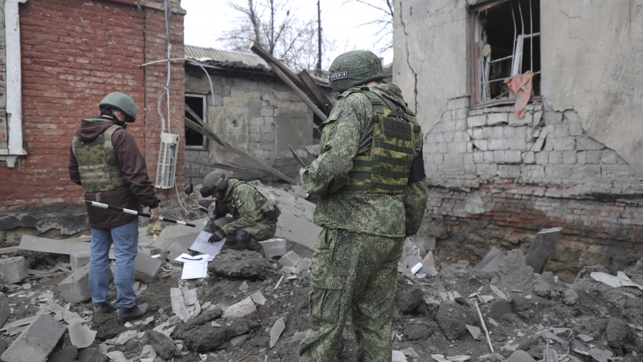Investigators inspect a site of an apartment building after shelling