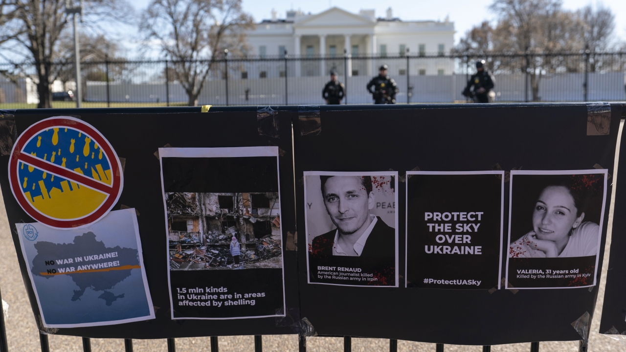 Signs and pictures of those killed, including journalist Brent Renaud, are displayed on a fence during a protest