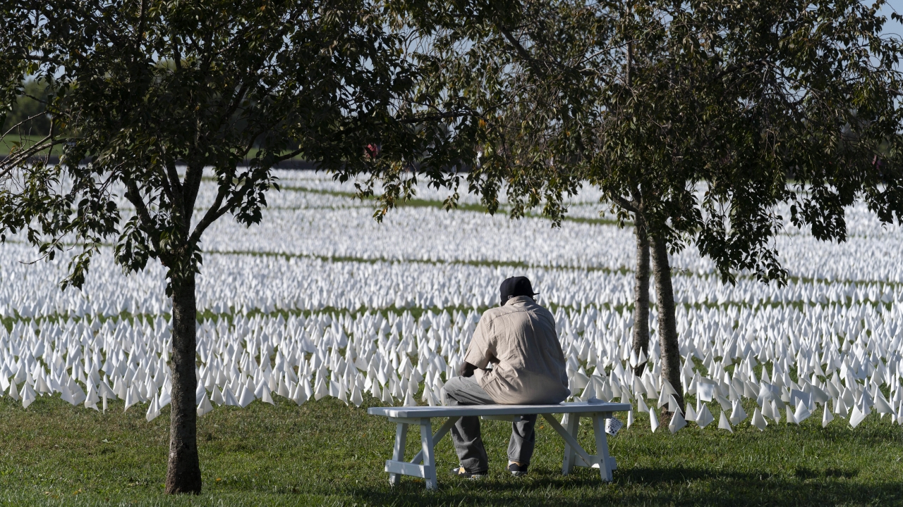 A visitor sits on a bench to look artist Suzanne Brennan Firstenberg's "In America: Remember," a temporary art installation