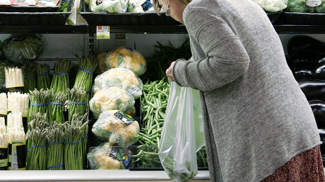 A person shops for vegetables at a grocery store.