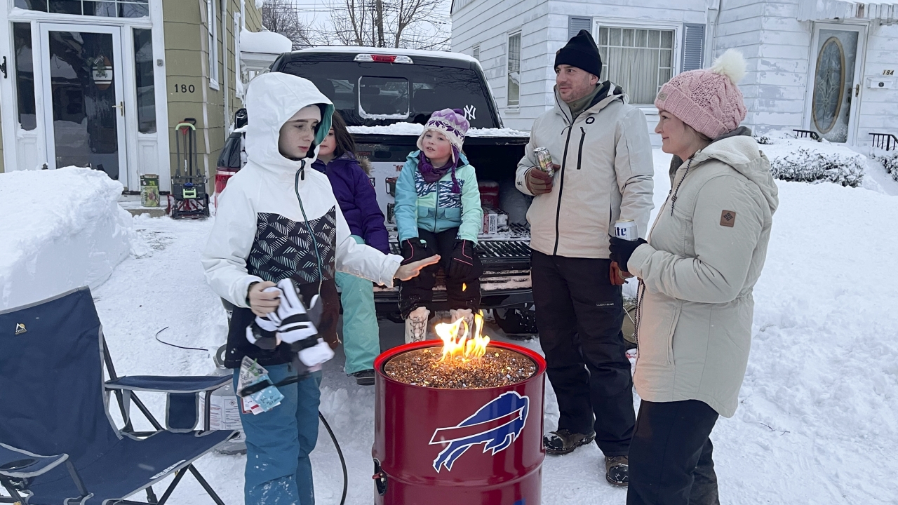 A group of neighbors gather around a fire pit on Culver Road after clearing snow in Buffalo, N.Y.,