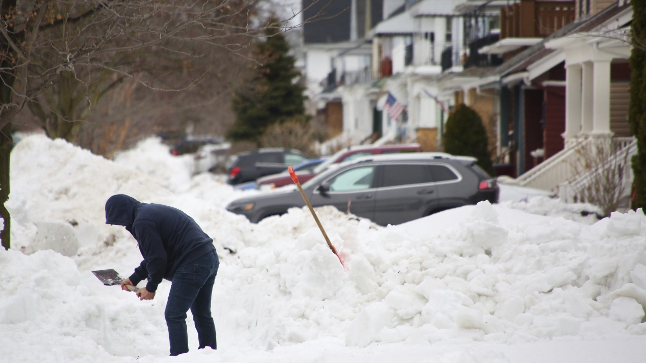 A man removes snow from the front of his driveway.