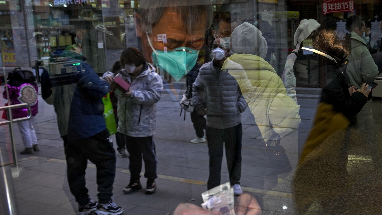 Visitors are reflected on a window pane as a man counts Chinese currency notes