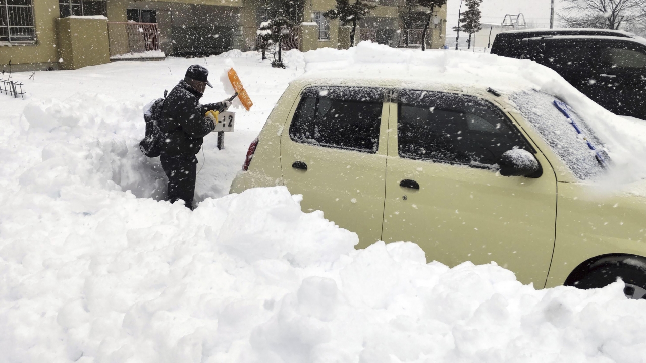 A resident shovels snow off a car.