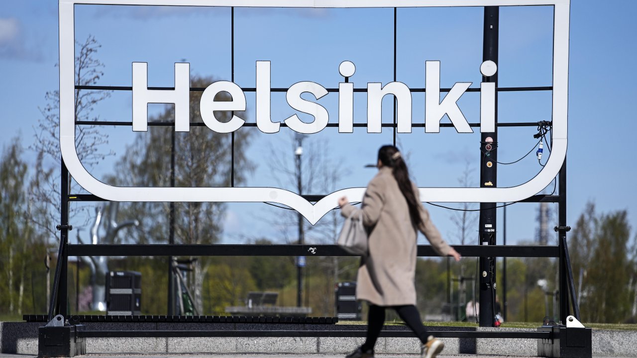 A woman passes a city sign in Helsinki, Finland