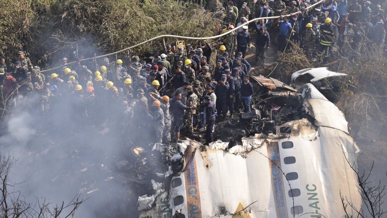 Nepalese rescue workers and civilians gather around the wreckage of a passenger plane that crashed in Pokhara, Nepal.