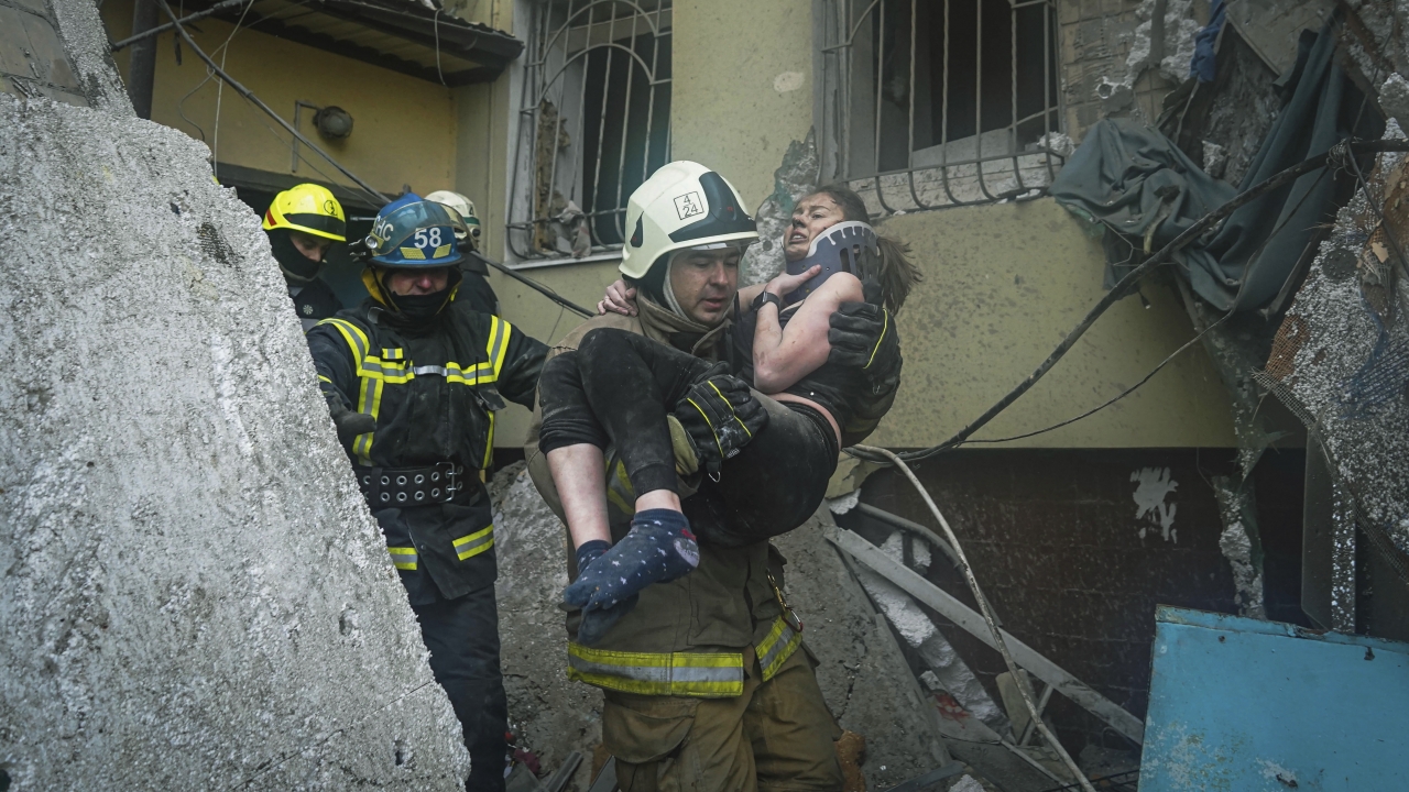 A Ukrainian State Emergency Service firefighter carries a wounded woman out of the rubble