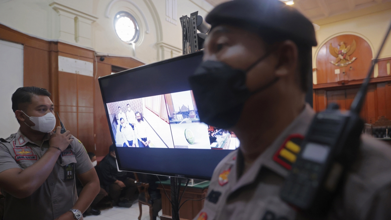 Police officers stand near a monitor inside a court room during a trial in Surabaya, East Java, Indonesia.