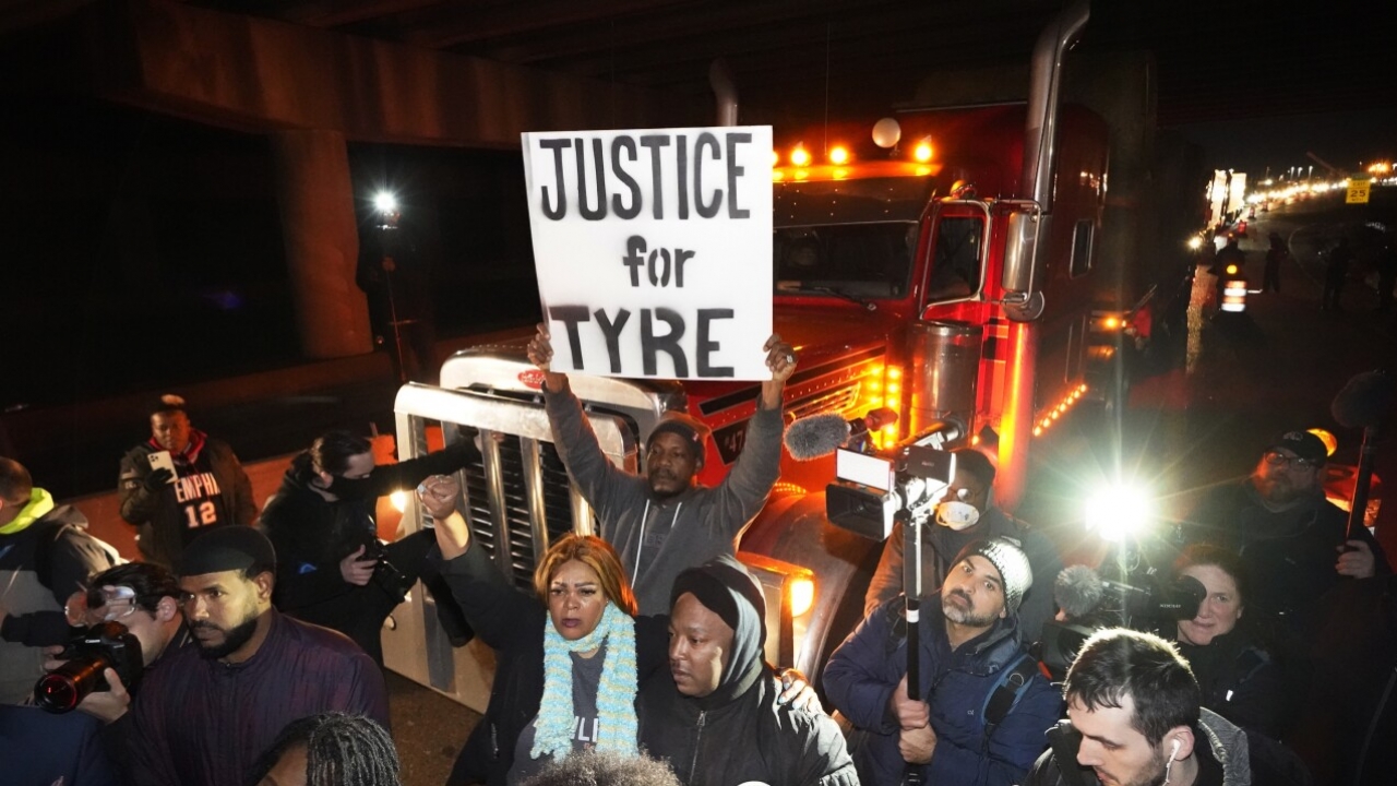 Protesters march down a street holding a "Justice for Tyre" sign.