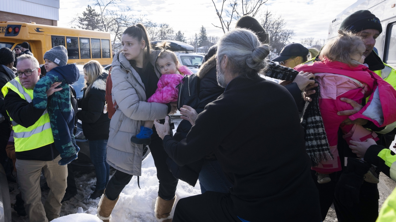 Parents and their children are loaded onto a warming bus as they wait for news after a bus crashed into a daycare center.