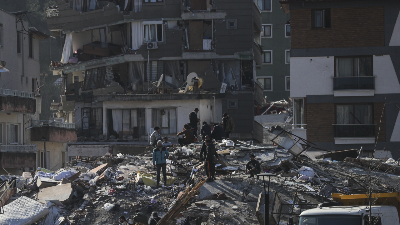 Men walk among the debris of collapsed buildings in Hatay, southern Turkey.