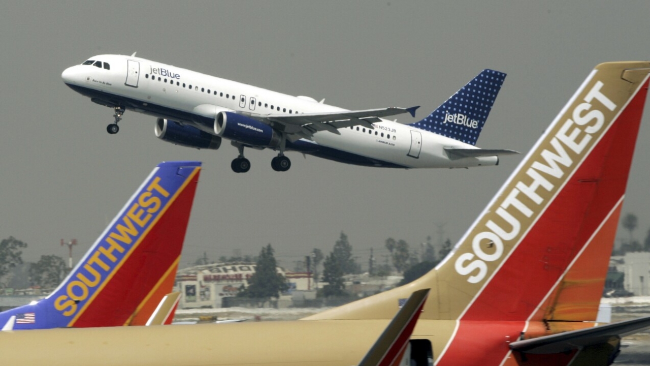 A JetBlue Airbus flies over a pair of Southwest Airlines' jets from Bob Hope Airport in Burbank, Calif.