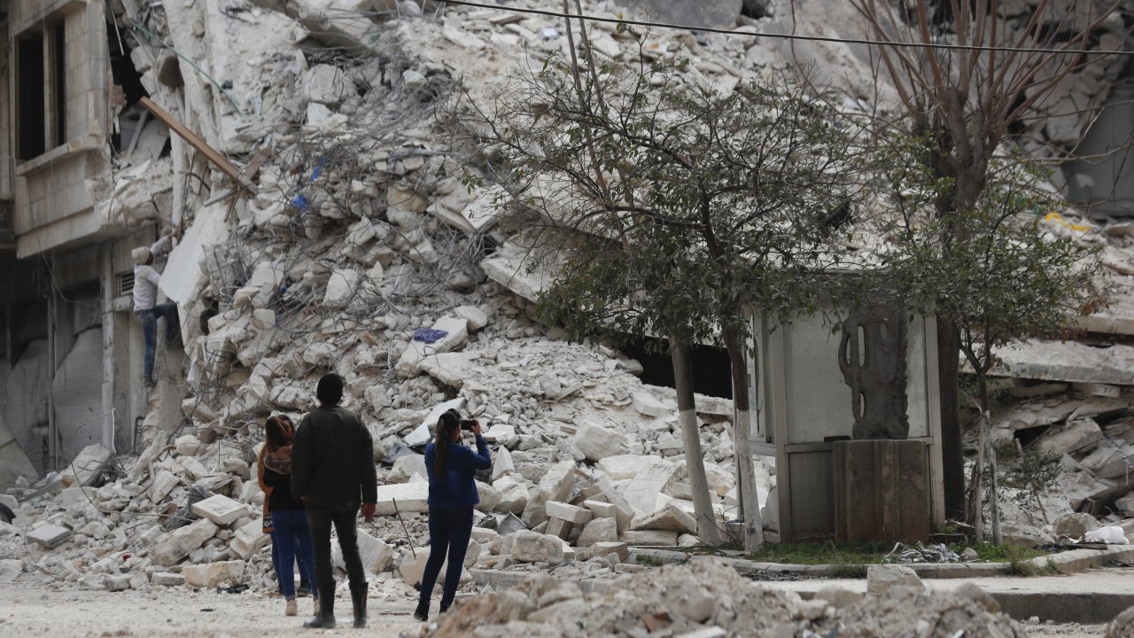 People stand by a building destroyed in recent earthquake in Aleppo, Syria, Monday, Feb. 27, 2023.