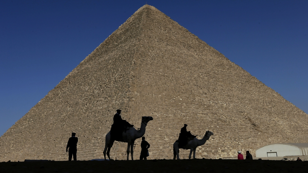 People and camels walk in front of the Great Pyramid of Giza