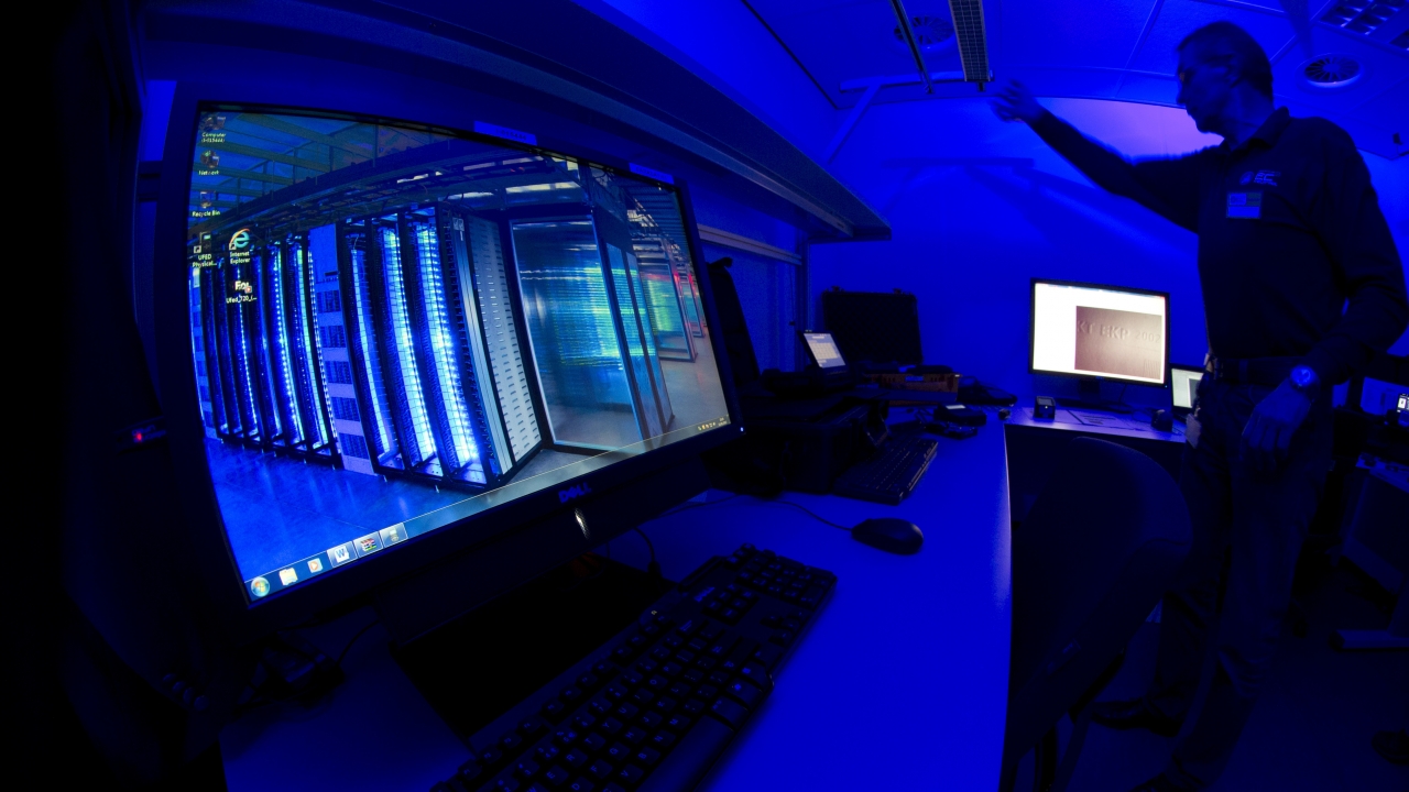 A man stands in front of screens at a cybercrime center.