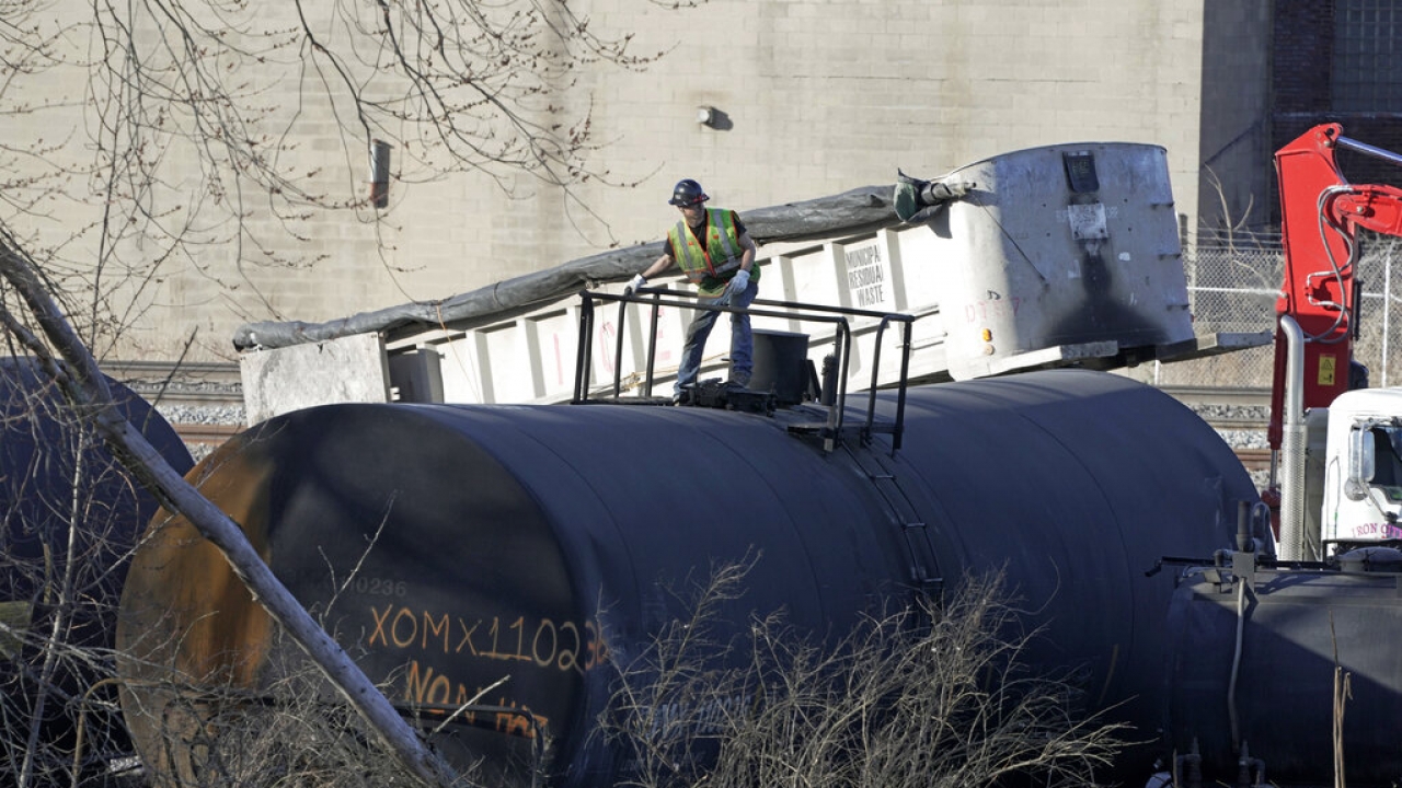 A cleanup worker stands on a derailed tank car as the cleanup of portions of a Norfolk Southern freight train.