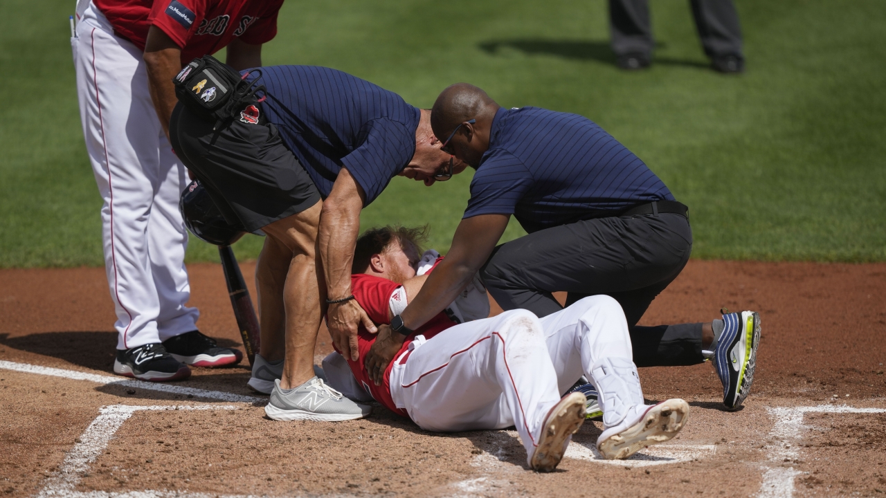 Boston Red Sox Justin Turner rolls on the ground after being hit in the face by a pitch.
