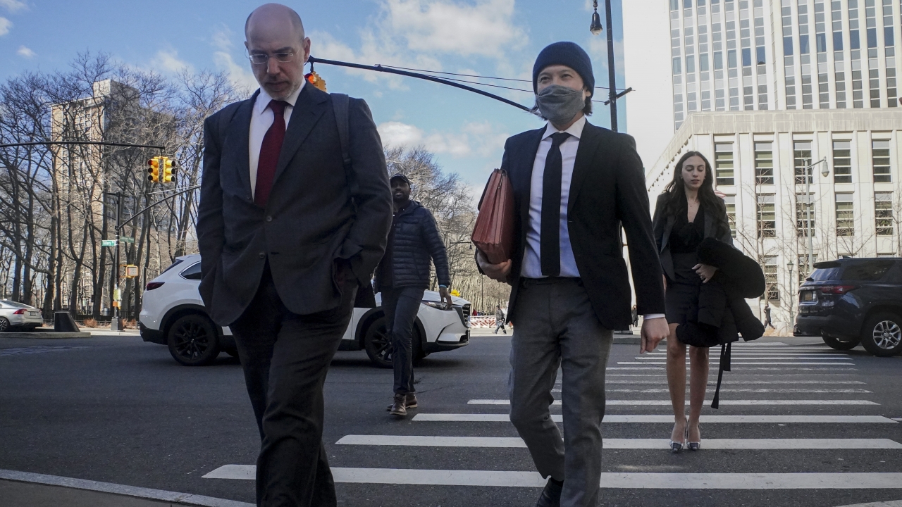 Roger Ng, center, a former Goldman Sachs banker, leaves federal court.