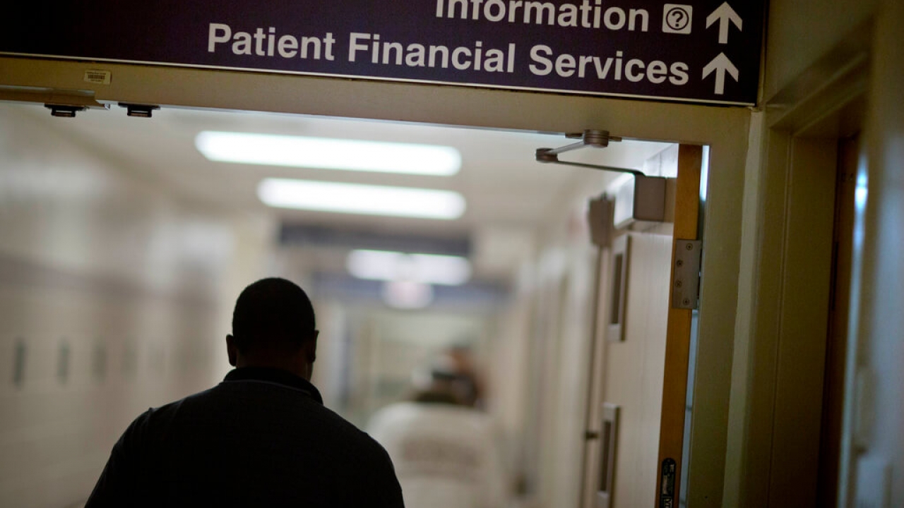 Man walks down a hospital hallway following a "patient financial services" sign