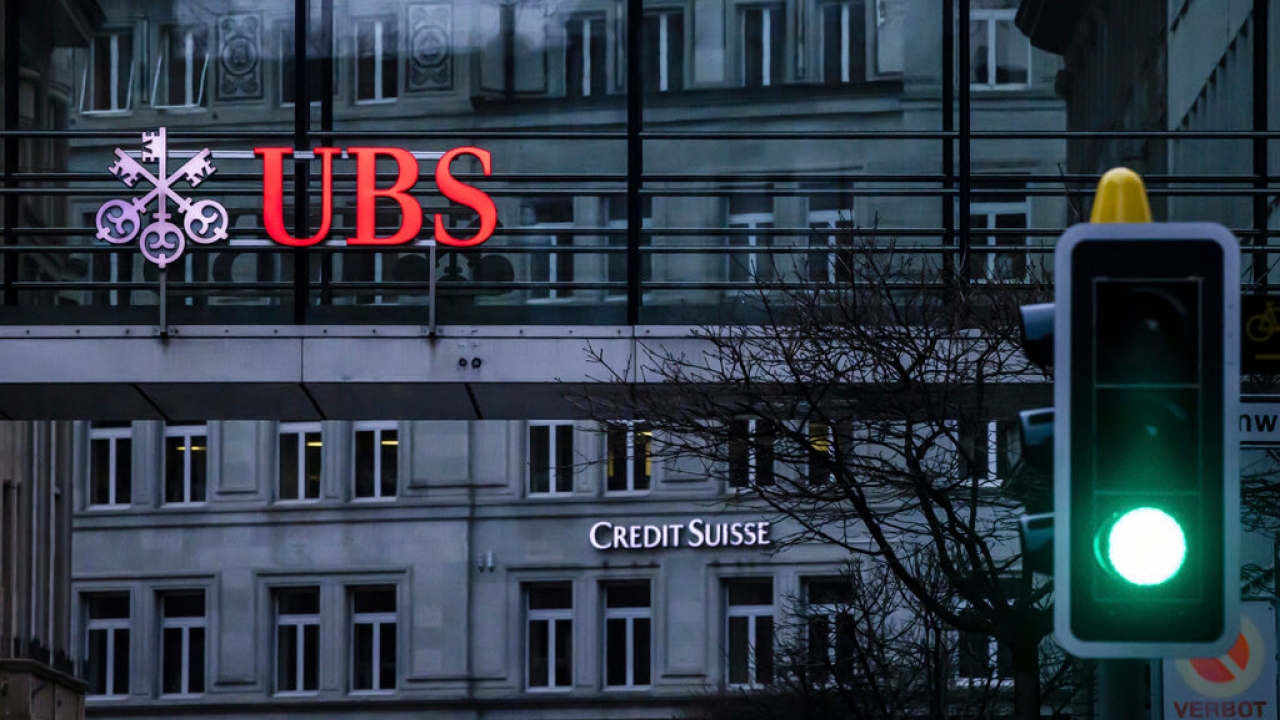 A traffic light signals green in front of the logos of the Swiss banks Credit Suisse and UBS in Zurich, Switzerland
