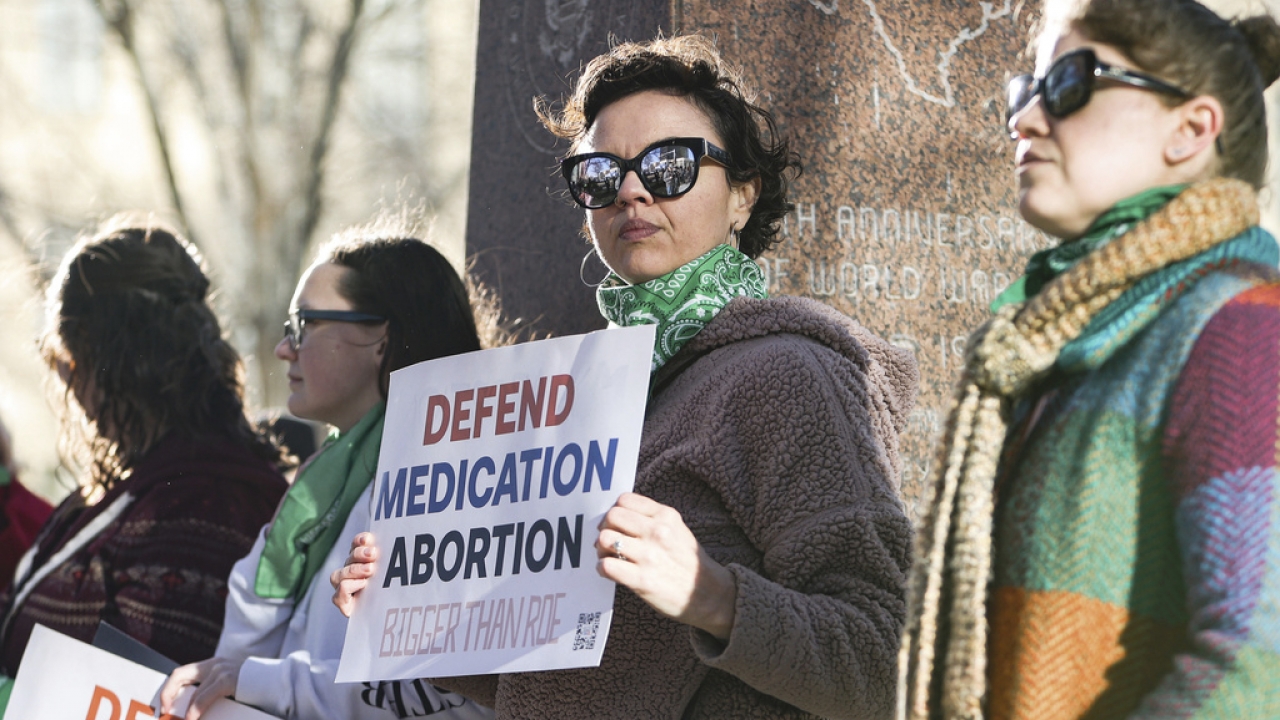 Demonstrators hold signs protesting abortion pill bans