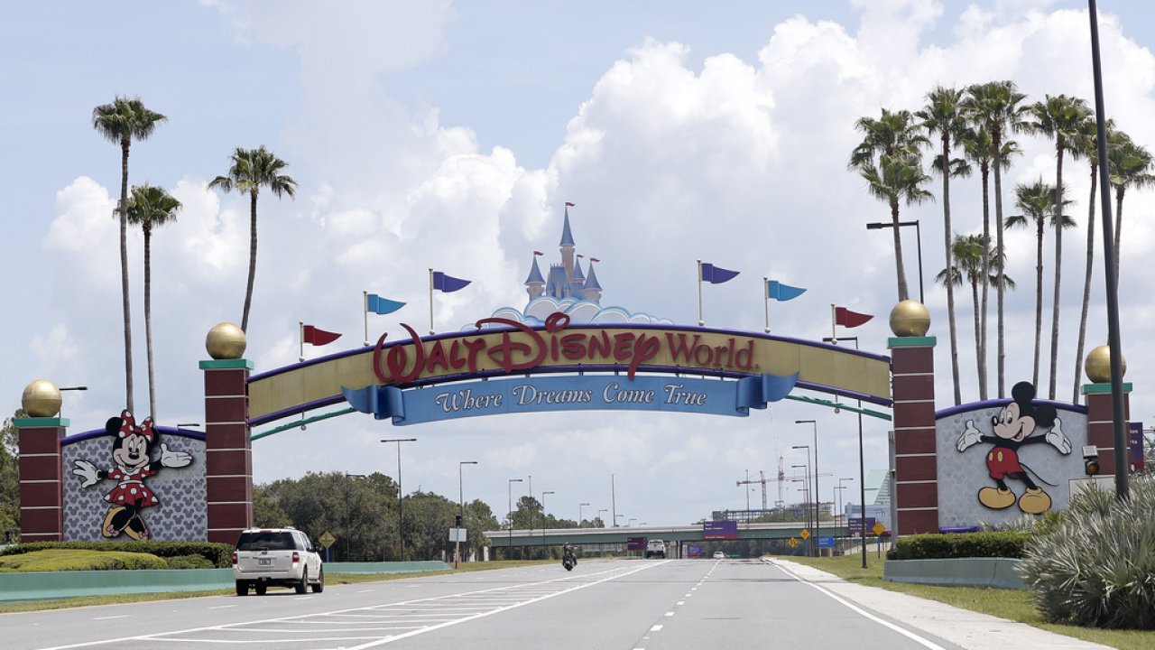 Cars drive under a sign greeting visitors near the entrance to Walt Disney World.