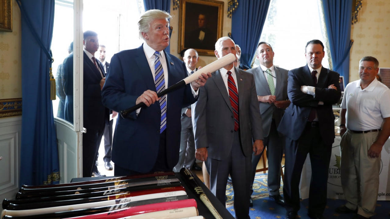 Former president Trump holds a baseball bat.