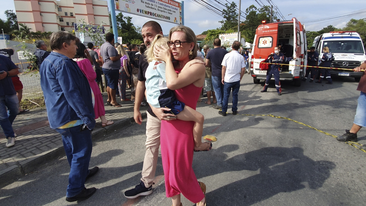A woman conforts a crying girl outside the daycare center "Cantinho do Bom Pastor."