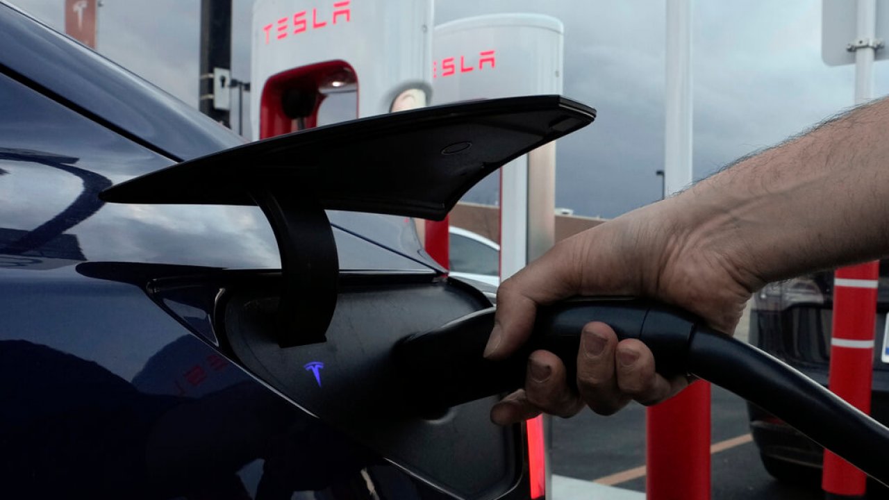 A motorist charges his electric vehicle at a Tesla Supercharger station.