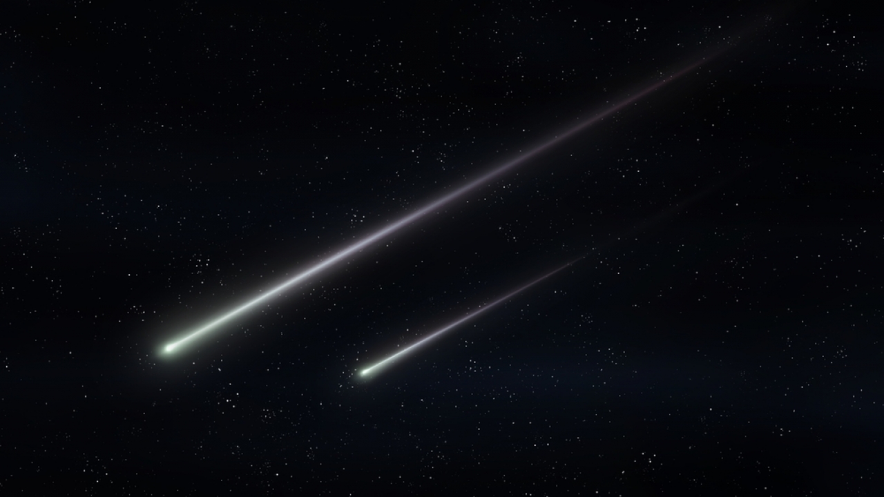 Two meteors fly in the night sky.
