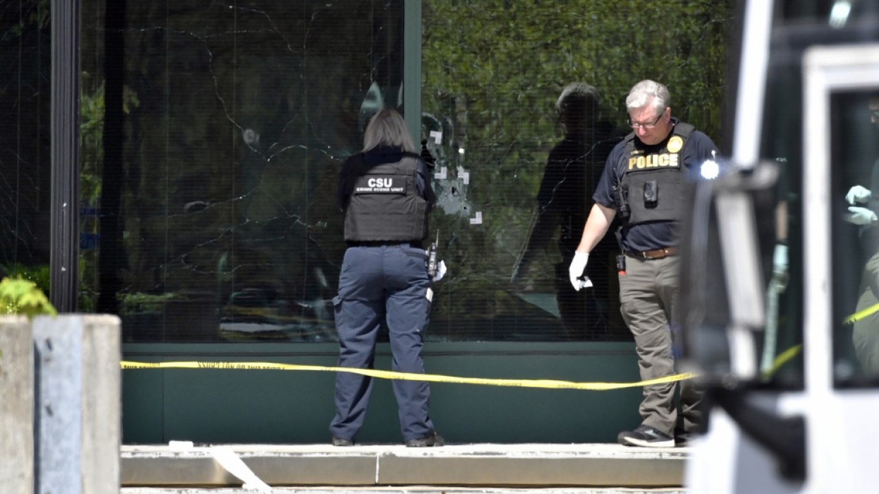 A Louisville Metro Police crime scene technician photographs bullet holes in the glass of the Old National Bank building.