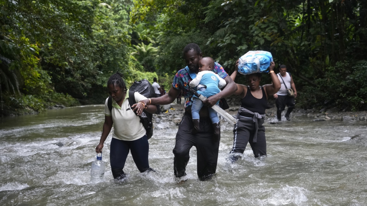 Migrants, mostly Venezuelans, cross a river during their journey through the Darien Gap.