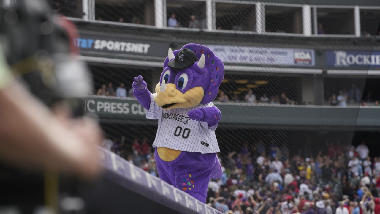 Colorado Rockies mascot Dinger the dinosaur waves to fans at the stadium.